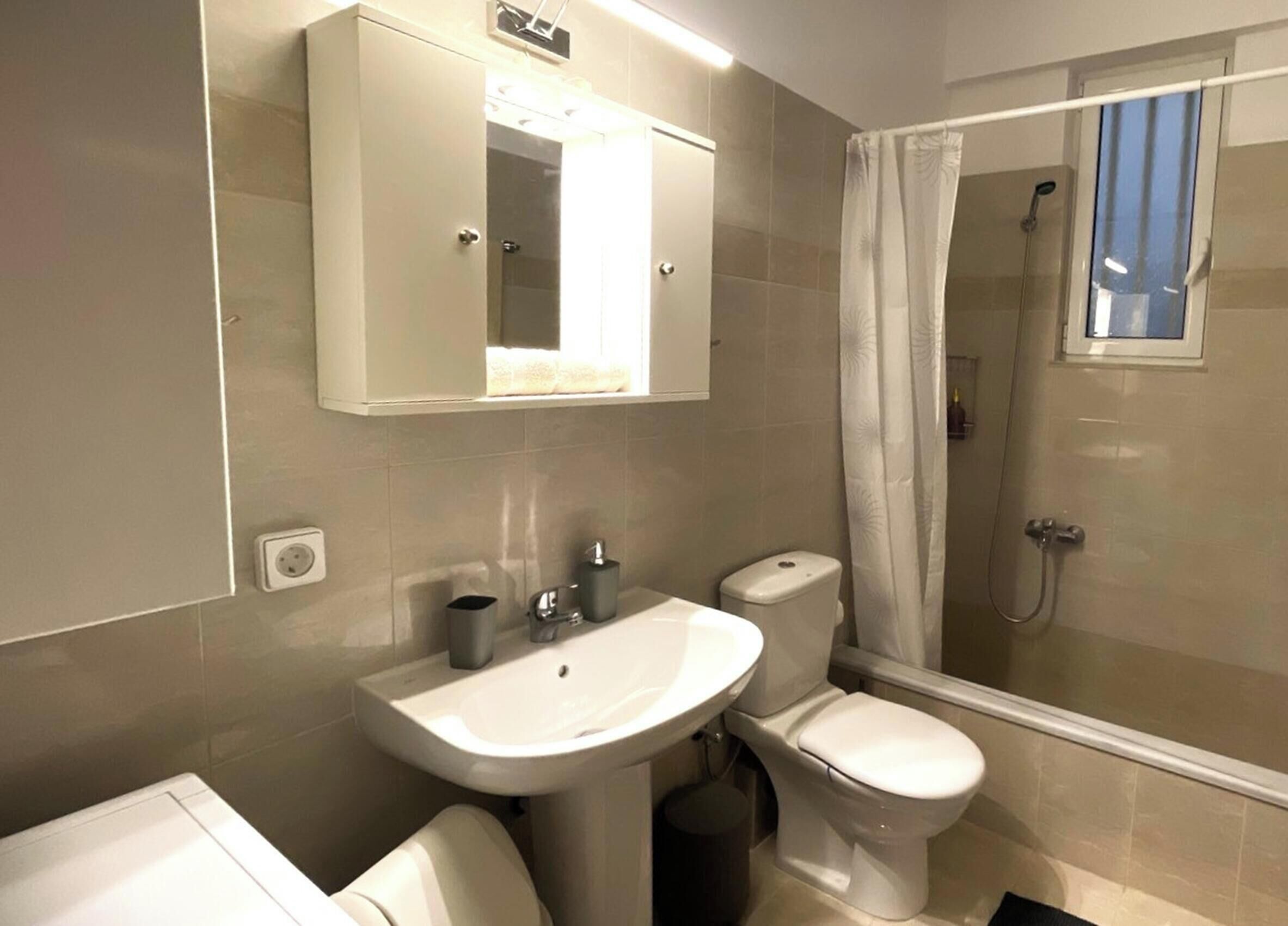 Et badeværelse med vask, toilet og brusebad.