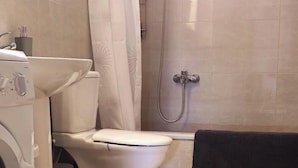 Ein Badezimmer mit Toilette, Dusche und Waschmaschine.