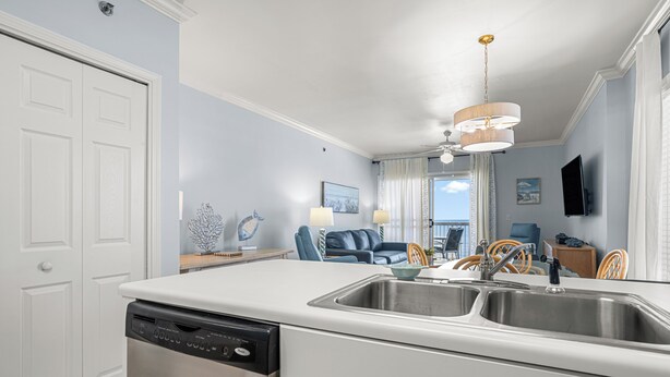 Una cucina moderna con lavastoviglie, doppio lavello e zona pranzo con divano blu e vista sul mare.