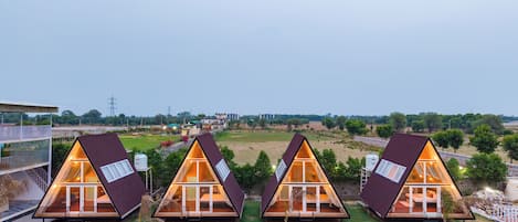 A row of triangular A-frame cabins with glass walls and a central courtyard.
