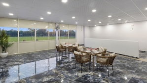 A conference room with a large table, chairs, and a view of a green landscape through large windows.