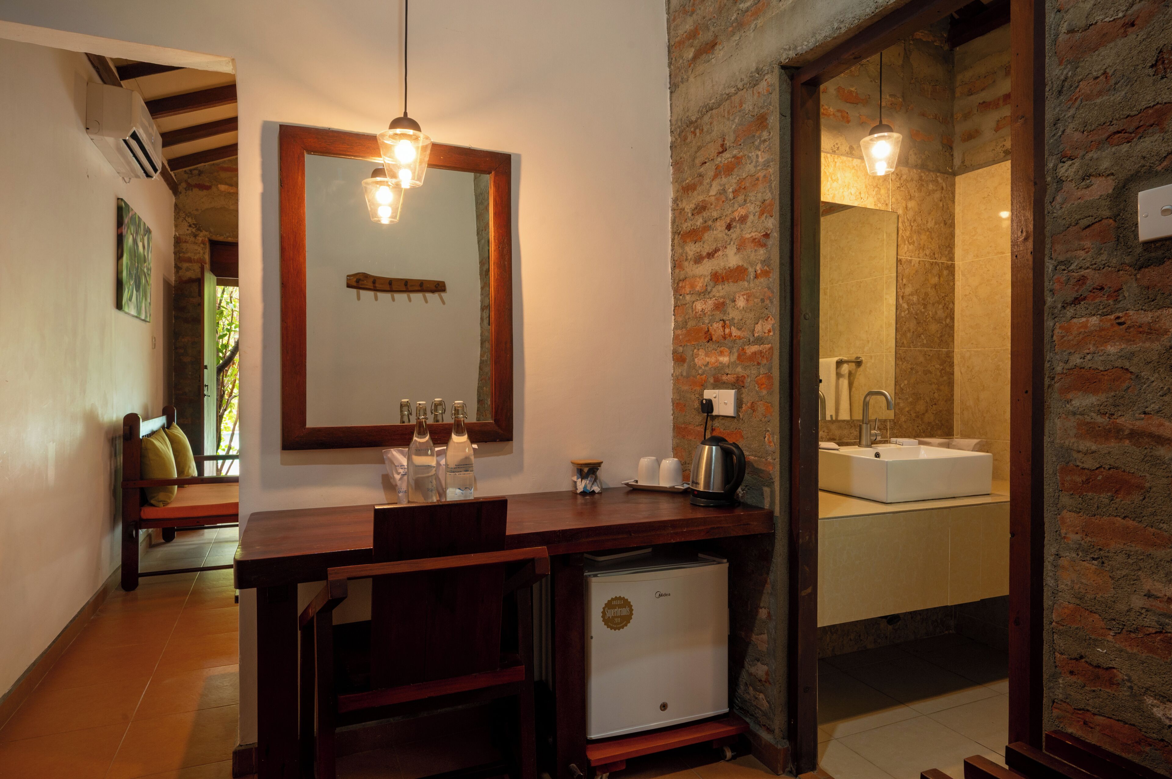 A compact bathroom with a wooden vanity, a mirror, a sink, and a compact refrigerator.