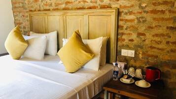 Ein Hotelzimmer mit einem Bett, Kissen, einem Nachttisch mit einer Wasserflasche, Tassen und einem roten Wasserkocher.