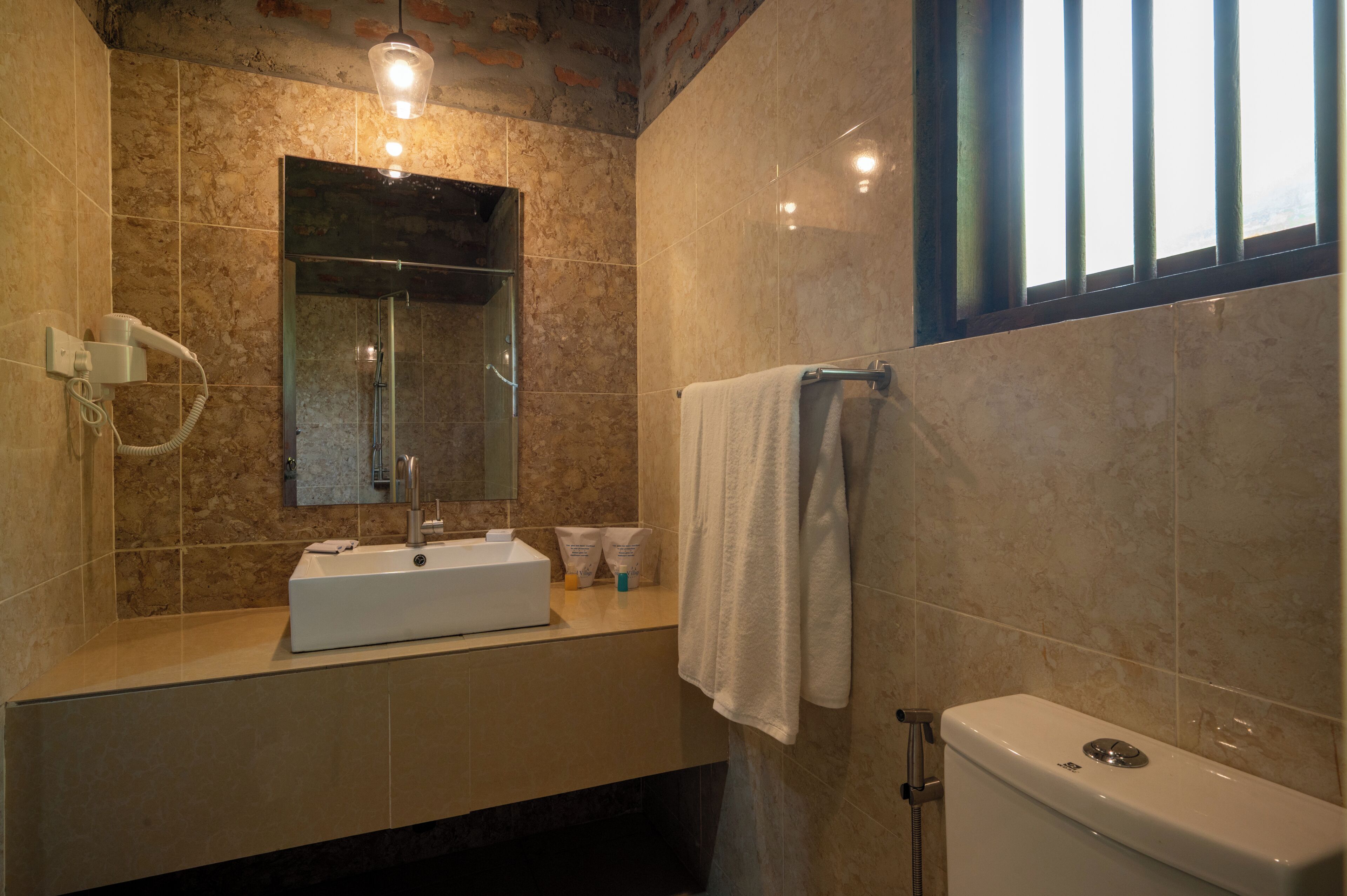 Un baño con lavamanos, espejo, toallero y retrete.