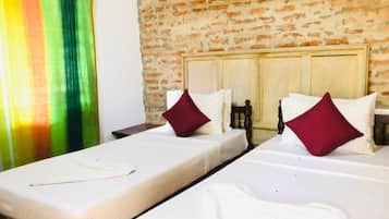 A hotel room with two beds, a brick wall, and a window with a curtain.