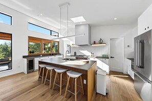 Eine moderne Küche mit einer großen Kochinsel, Barhocker, einem Einbauofen und einem Edelstahl-Kühlschrank.