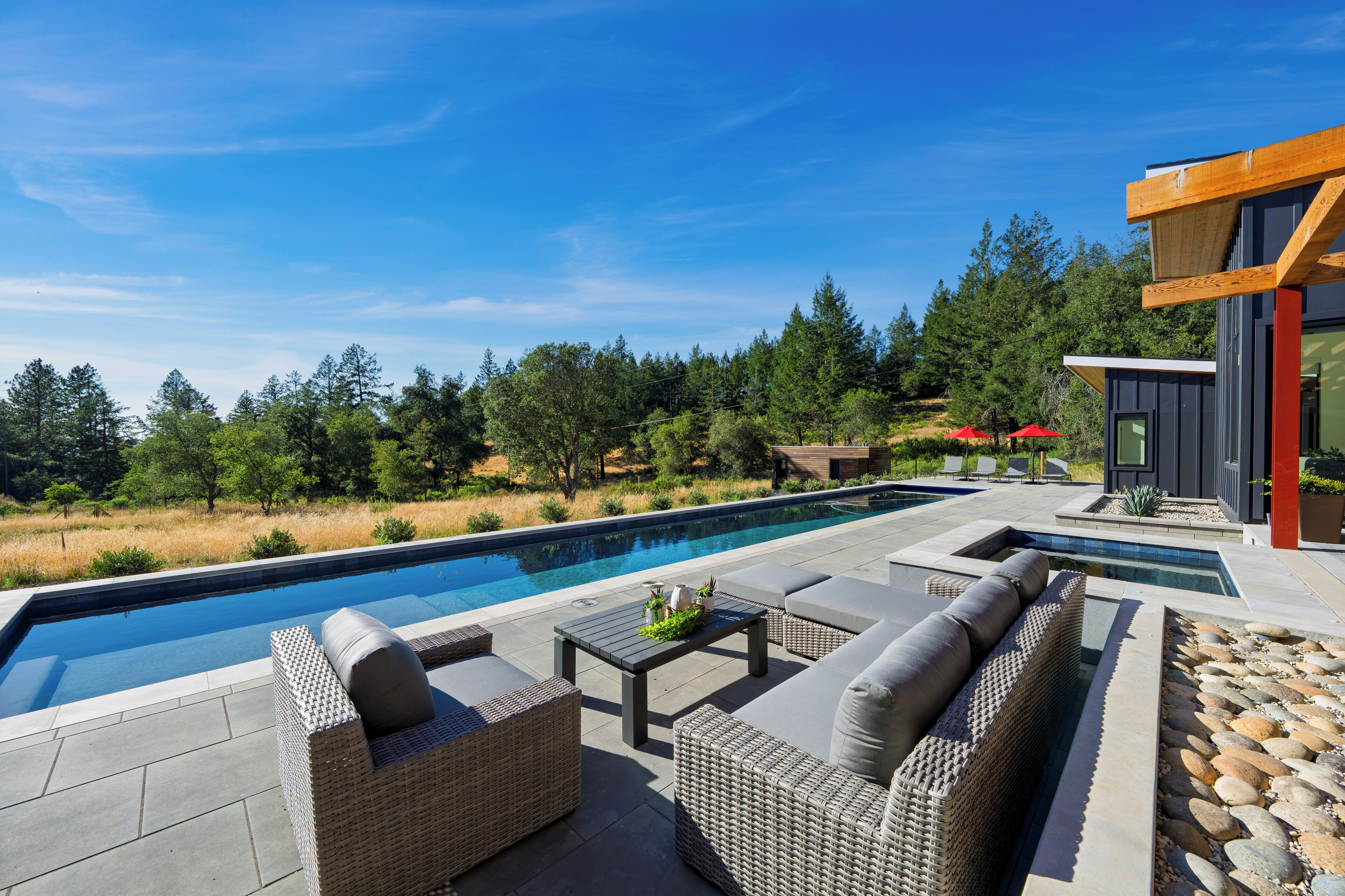 Un área de piscina exterior moderna con mobiliario de mimbre y un camino de piedra.