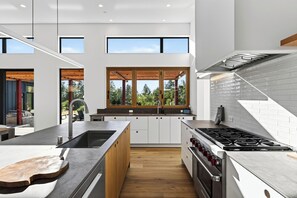 A modern kitchen with a large island, built-in appliances, and a view of the outdoors.
