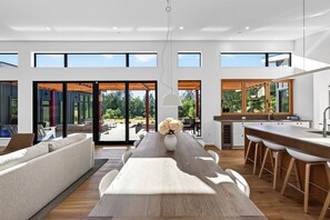 A spacious living area with a large dining table, comfortable seating, and a view of the outdoors.