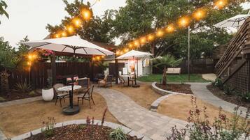 An outdoor patio area with string lights, a covered seating area, and a pathway.