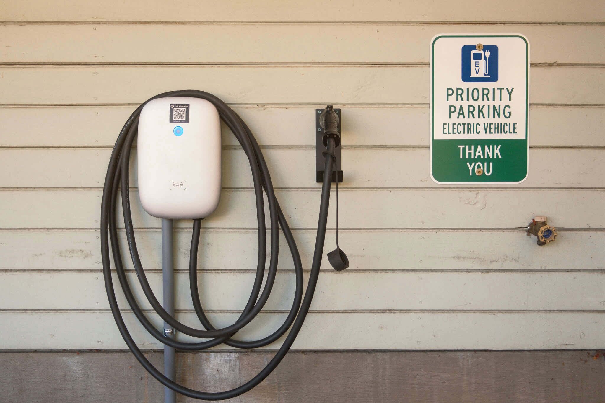 An electric vehicle charging station with a sign indicating priority parking for electric vehicles.