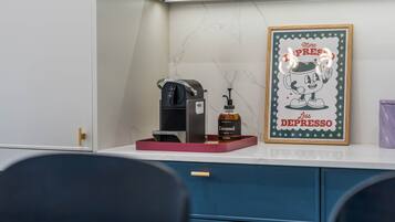 A coffee machine, a sugar-free caramel syrup bottle, and a framed motivational quote on a counter.