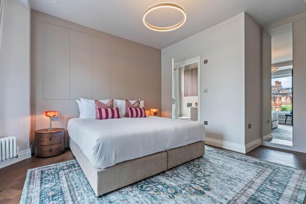 Un dormitorio moderno con una cama grande, lámparas de noche, un tapete estampado y vistas al exterior.