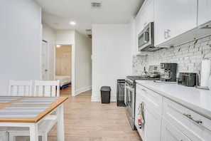 A compact kitchen with white cabinetry, a microwave, a stove, and a trash bin. - Near NYC Transit! Modern Gateway Region Apt (West New York)