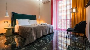 Una camera d'albergo con un letto, una sedia, un tavolino e una finestra con tende.