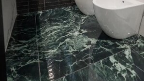 Un bagno con un lavandino bianco, un water e uno specchio. Il pavimento presenta un motivo marmoreo bianco e nero.