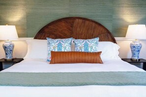 Una cama con cabecera de madera, dos lámparas de noche y jarrones decorativos sobre las mesitas.
