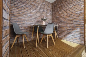 A corner room with a brick wall, two grey chairs, a small table, and a vase with flowers. - WhiskAwayStays - Arboretum ground floor apartment (Worcestershire)