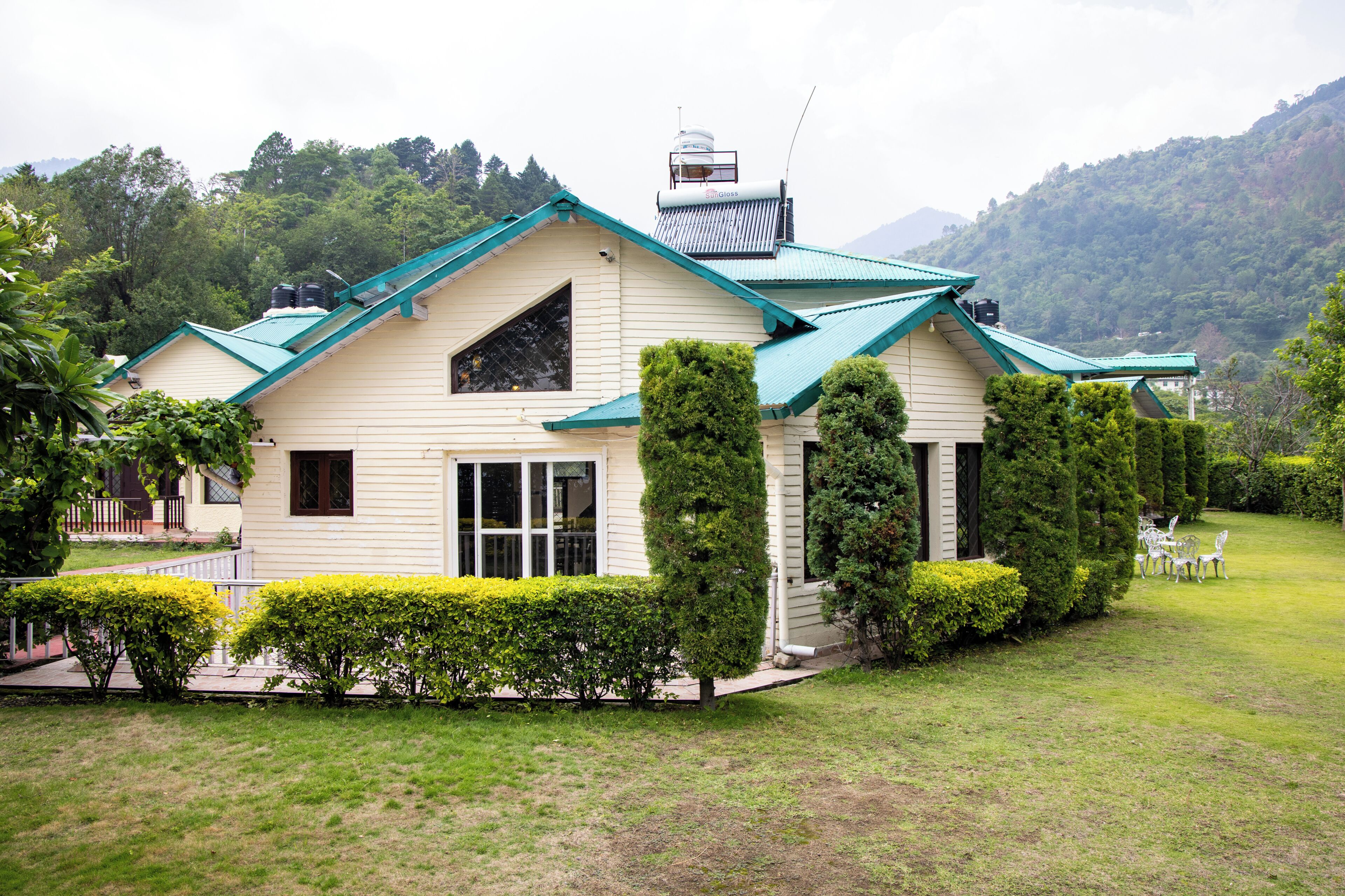 Una casa con techo inclinado, chimenea y césped cuidado.