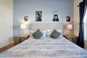 Een hotelkamer met een groot bed, twee nachtkastjes, een hoofdbord en drie ingelijste foto's aan de muur.