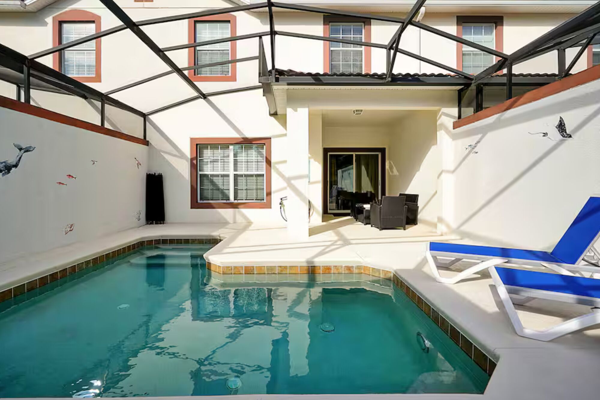 A swimming pool with a glass ceiling, a covered patio area, and a view of the surrounding buildings.