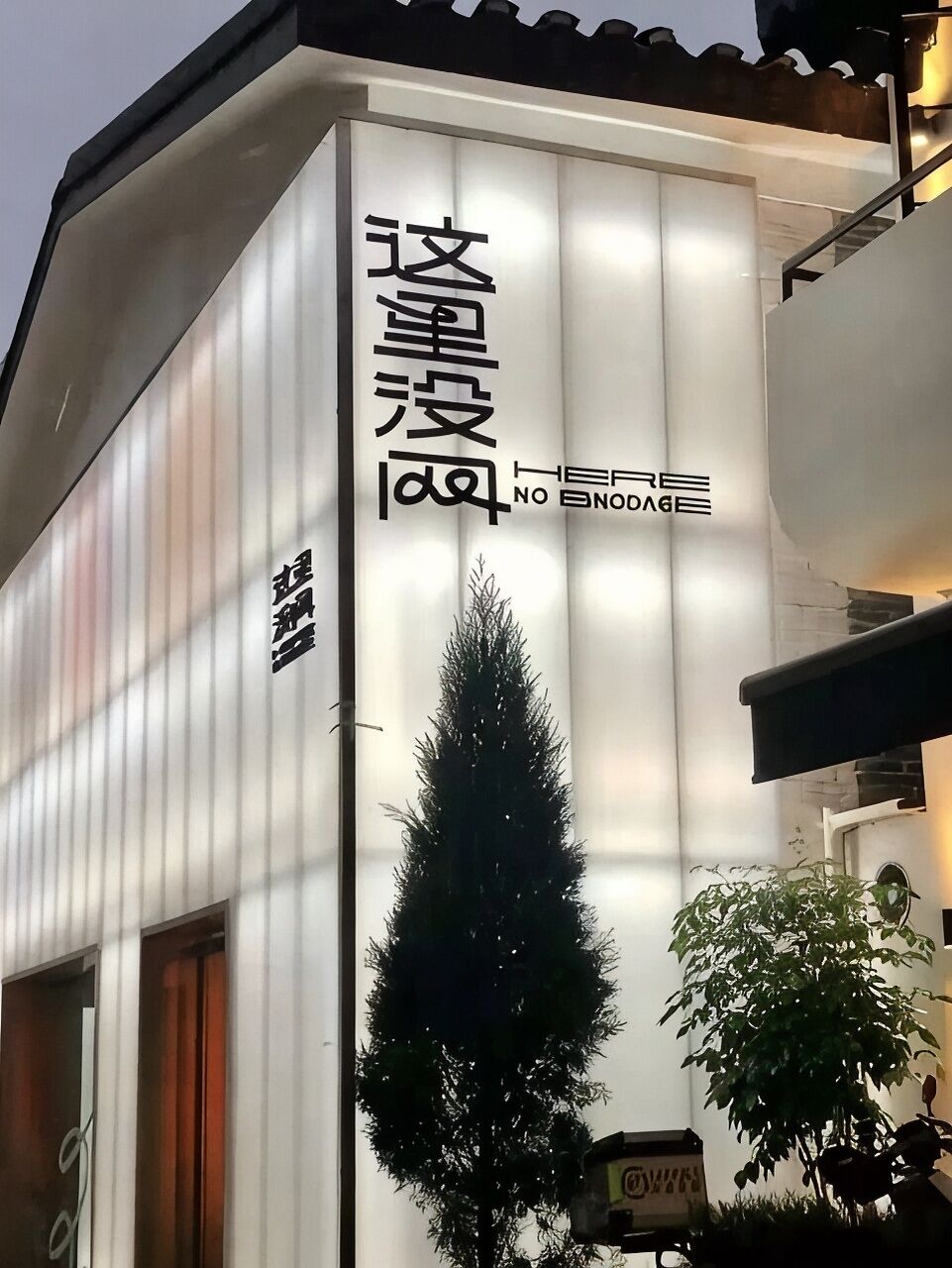Fachada de edificio con paneles verticales y un letrero con caracteres chinos.