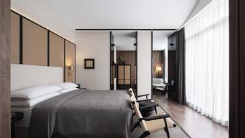 Una habitación de hotel moderna con una cama grande, un escritorio y vistas de la ciudad a través de cortinas translúcidas.