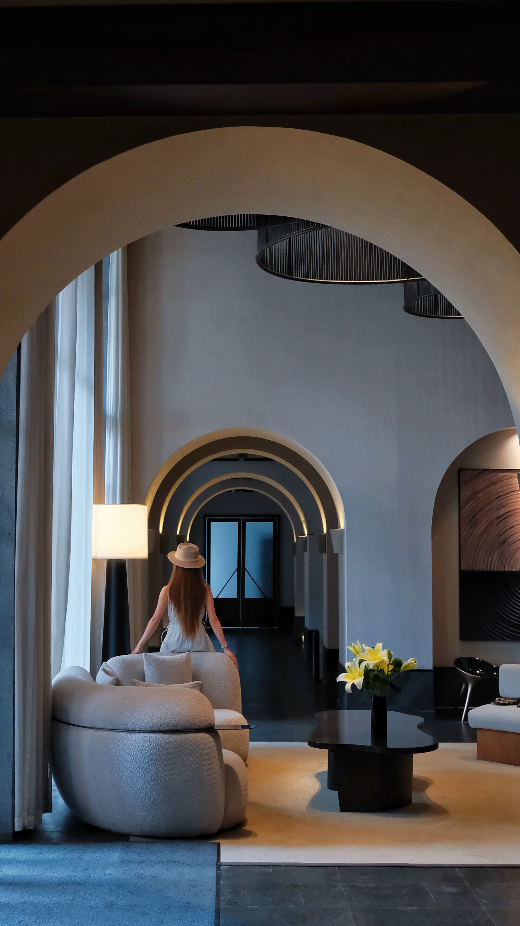 A modern interior with a sofa, a table with flowers, and a lamp.