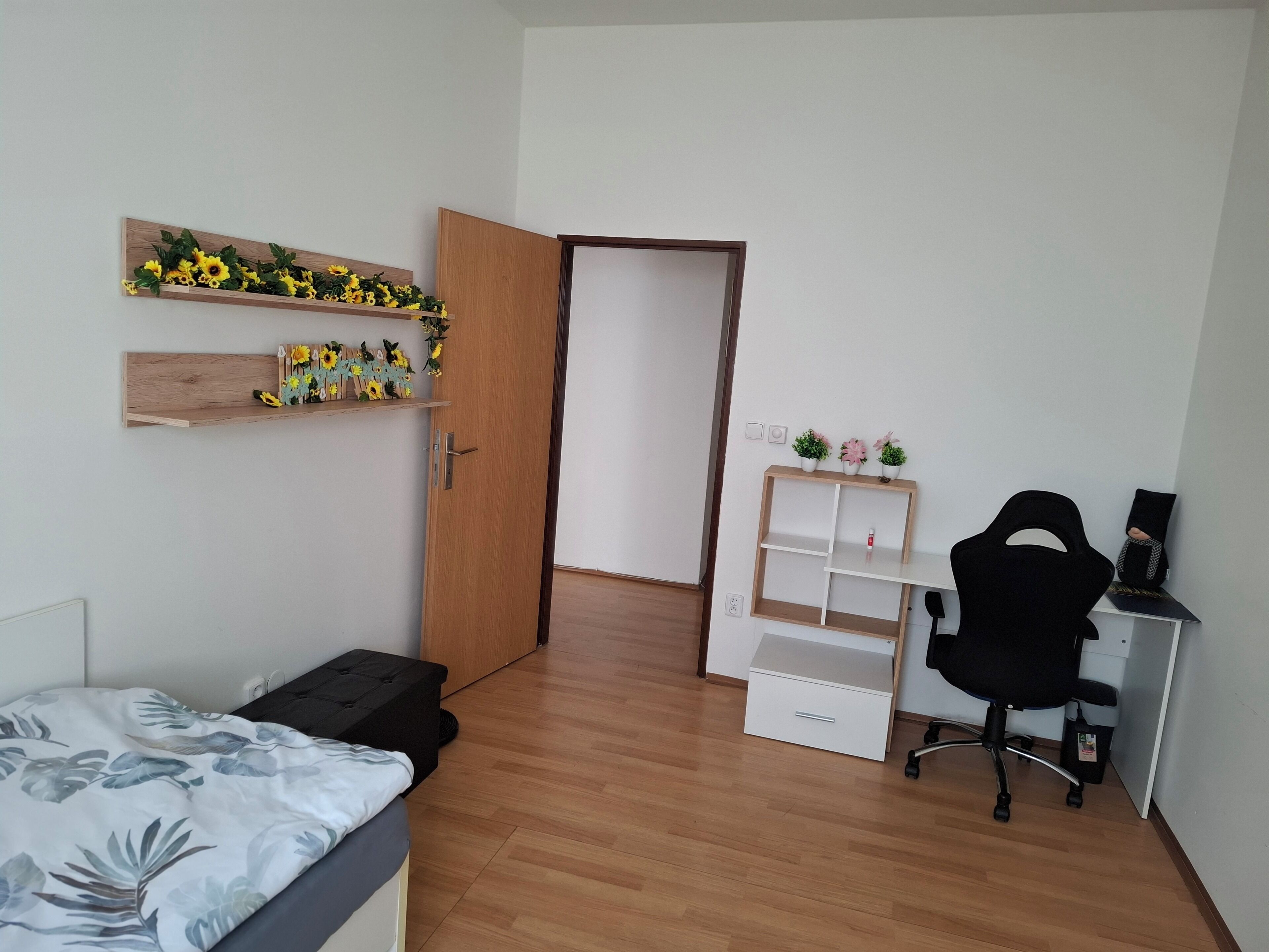 A bedroom with a bed, a desk, a chair, and a wardrobe.