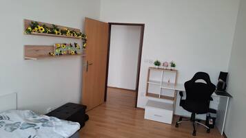 A bedroom with a bed, a desk, a chair, and a wardrobe.