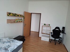 A bedroom with a bed, a desk, a chair, and a wardrobe.