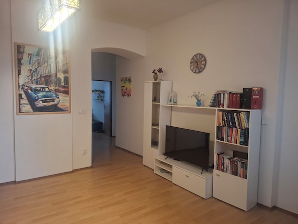 A living room with a TV, bookshelf, and artwork on the wall.