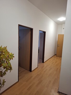 A hallway with wooden flooring and white walls, leading to two doors.