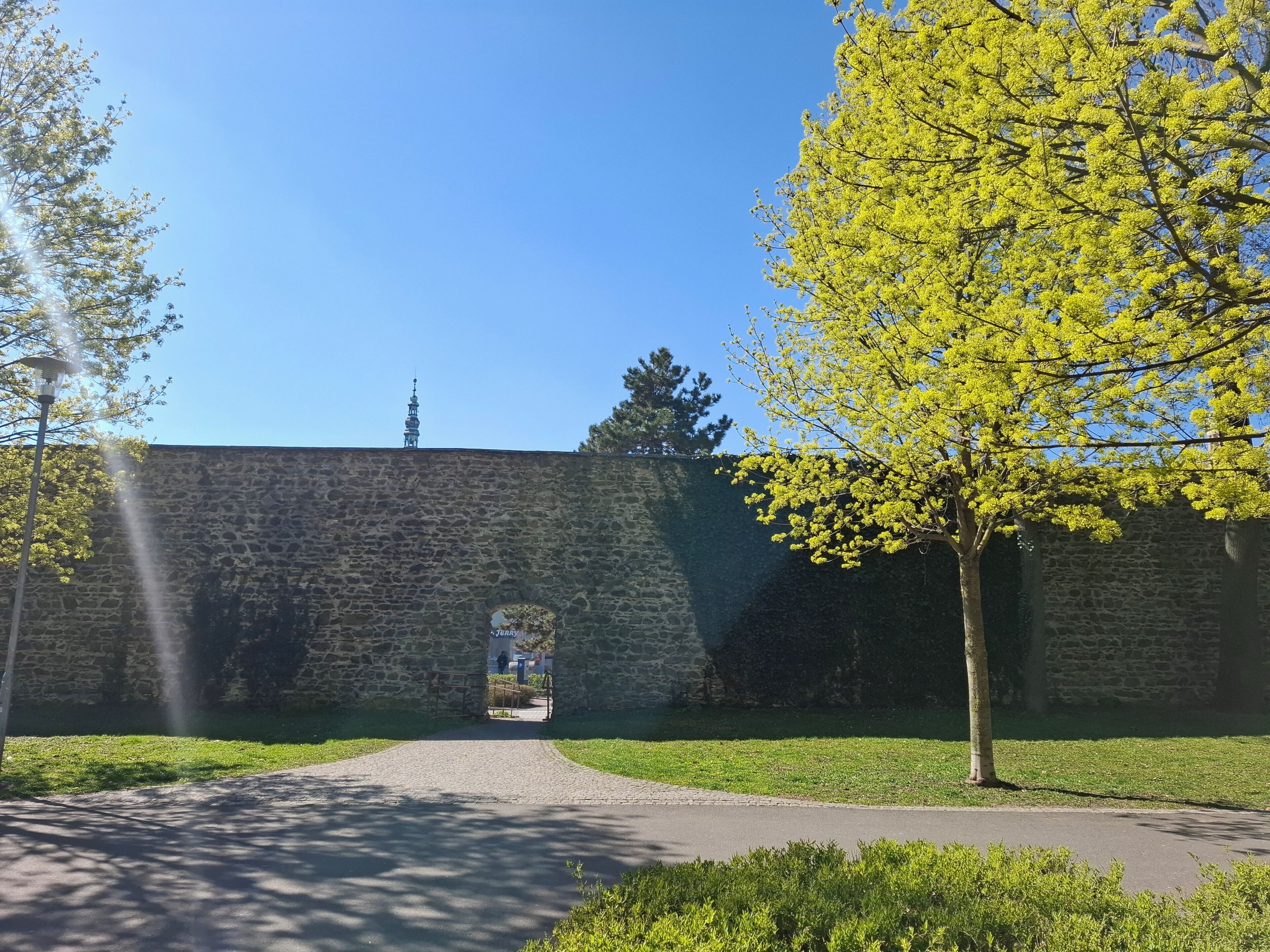 A stone wall with a gate leading to a building.