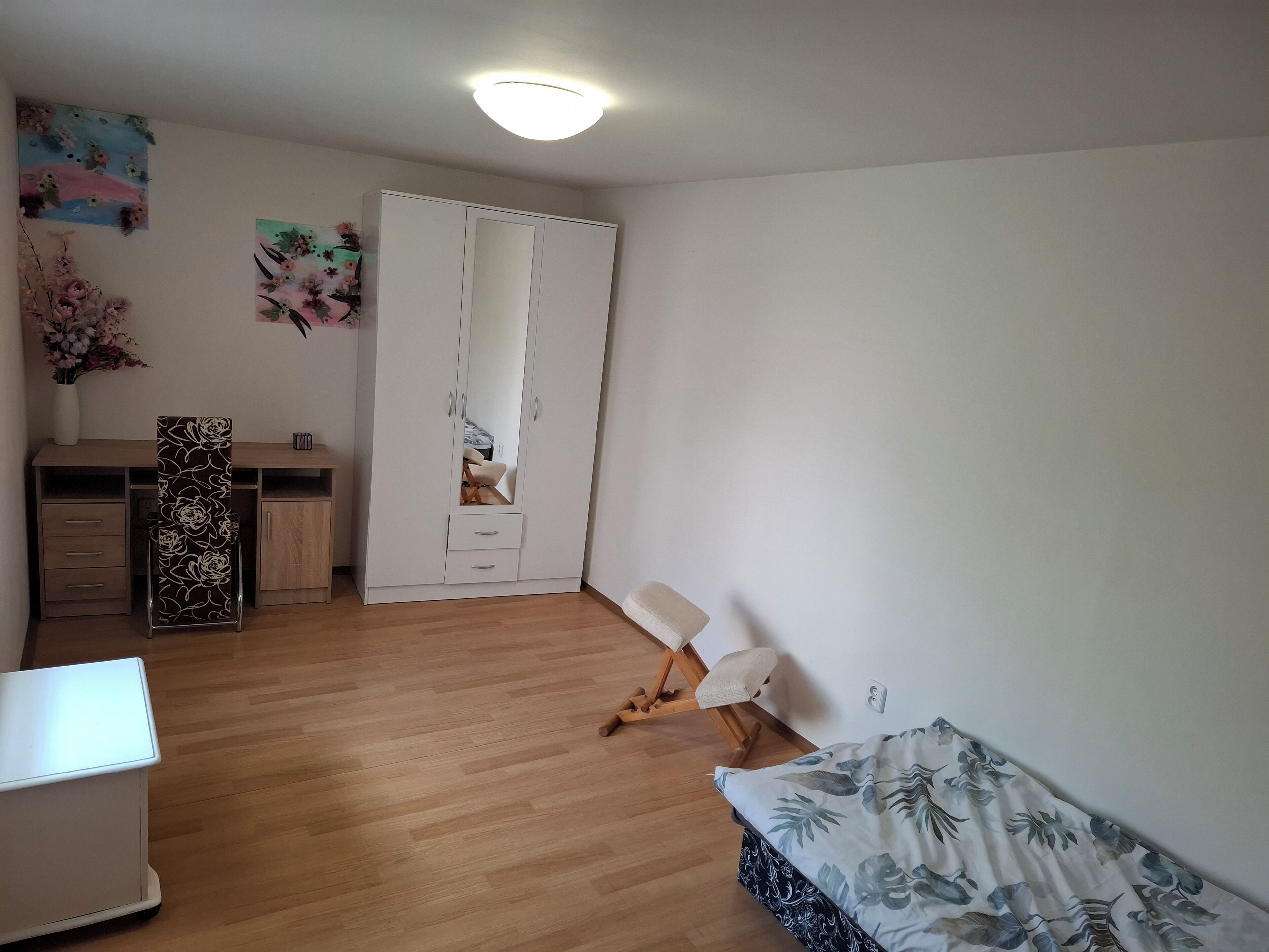 Ein Schlafzimmer mit einem Bett, einem Schreibtisch, einem Kleiderschrank und einem Stuhl.