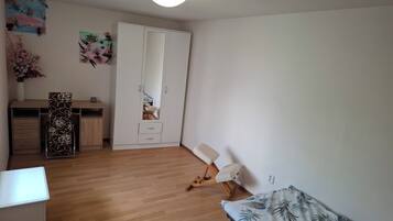 Ein Schlafzimmer mit einem Bett, einem Schreibtisch, einem Kleiderschrank und einem Stuhl.