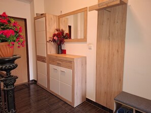 A hallway with a wooden cabinet, a potted plant, a mirror, and a bench.