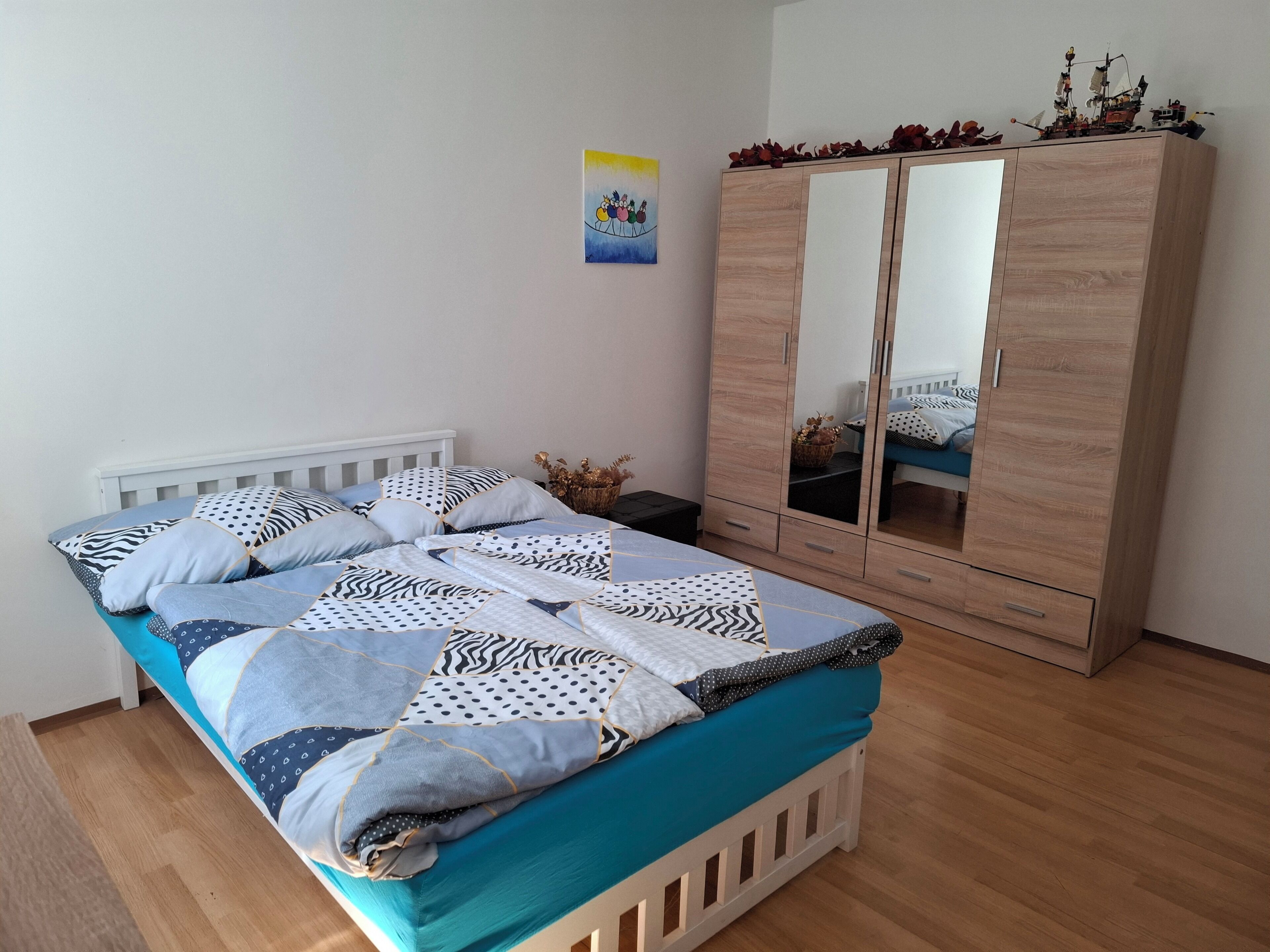 Ein Schlafzimmer mit einem Bett, einem Kleiderschrank und einem an der Wand hängenden Kunstwerk.
