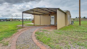 A small, single-story building with a metal roof and a door, surrounded by a gravel path and grass. - Tranquil Wine Country Getaway w/ Hillside Views (Elgin)