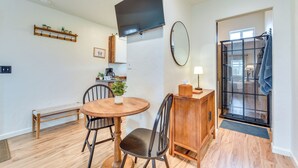 A dining area with a round wooden table, chairs, a bench, a small cabinet, a mirror, and a television mounted on the wall. - Tranquil Wine Country Getaway w/ Hillside Views (Elgin)