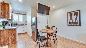 A modern kitchen with white cabinets, a stainless steel refrigerator, and a wooden dining table with two chairs. - Tranquil Wine Country Getaway w/ Hillside Views (Elgin)