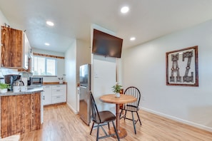 A modern kitchen with white cabinets, a stainless steel refrigerator, and a wooden dining table with two chairs. - Tranquil Wine Country Getaway w/ Hillside Views (Elgin)