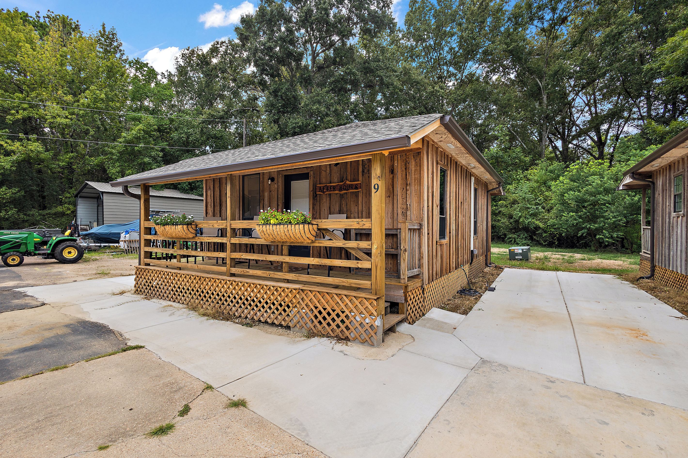 A wooden cabin with a porch, a number '9' sign, and a John Deere tractor in the background.