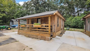 A wooden cabin with a porch, a number '9' sign, and a John Deere tractor in the background.
