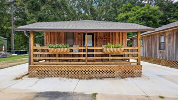 A wooden cabin with a porch, a sign reading 'AFTER HOURS', and two flower baskets.