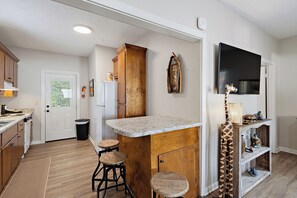A kitchen with a wooden island, bar stools, a mounted television, and a giraffe sculpture.