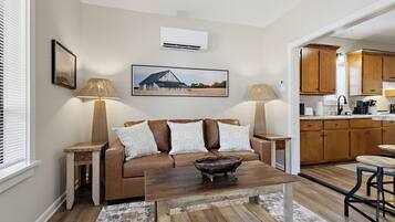 A living room with a brown leather sofa, two lamps, a coffee table, and a painting on the wall.