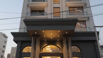 Un hotel de varios pisos con una entrada destacada, ventanas amplias y un letrero que indica que es el 'Grand Plaza Hotel'.