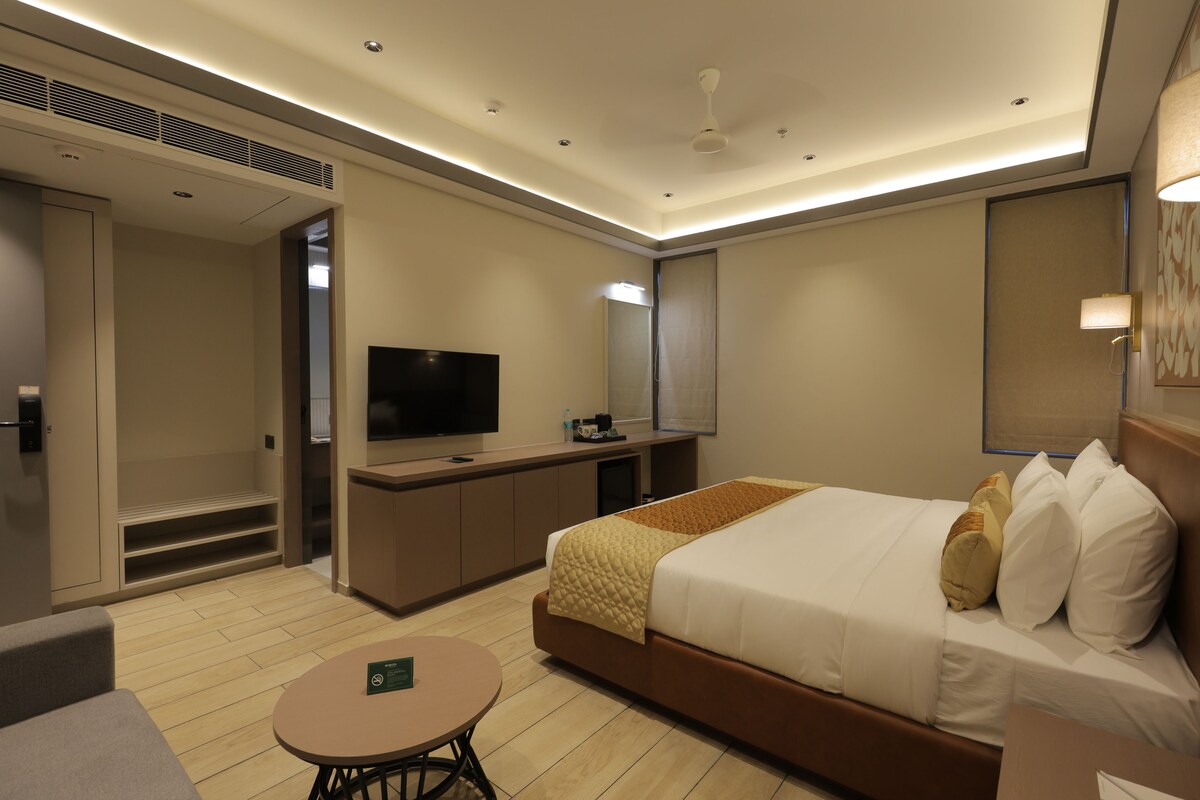 Una habitación de hotel con cama, televisión, escritorio y una pequeña mesa.
