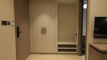 Une chambre d’hôtel équipée d’un placard, d’une télévision et d’un petit coin salon.